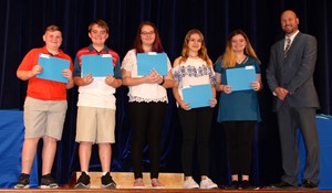 Students pose with principal on stage at awards ceremony