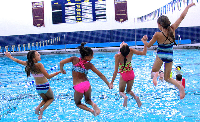 four girls jump in pool hand in hand
