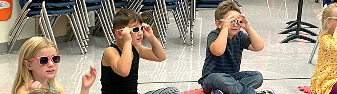 Students in sunglasses seated on floor singing