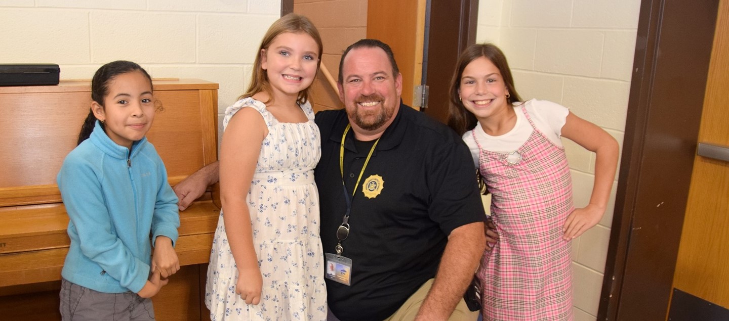 Four Brookside Elementary students surround their beloved S R O  in the cafeteria.