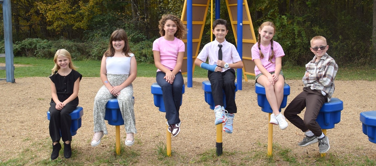 Six Brookside Elementary students strike a similar post as they sit on the playground.