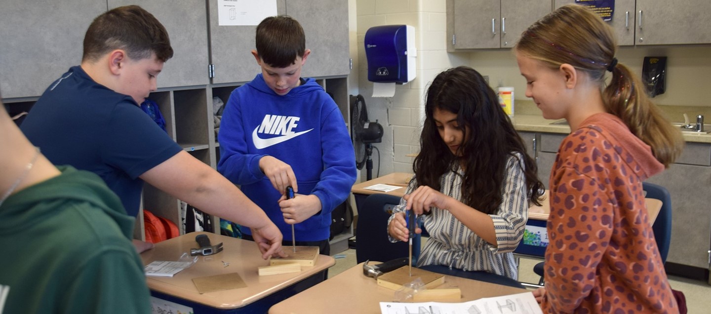 Four Brookside Elementary third-graders work together to build bird feeders