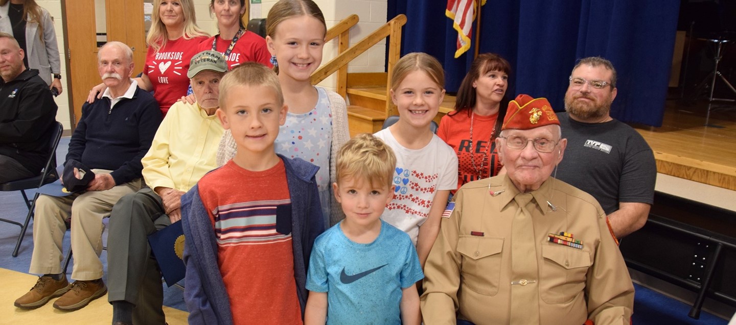 Great grandchildren of a World War two Marine veteran gather around him following a Veterans Day ceremony at Brookside Elementary.