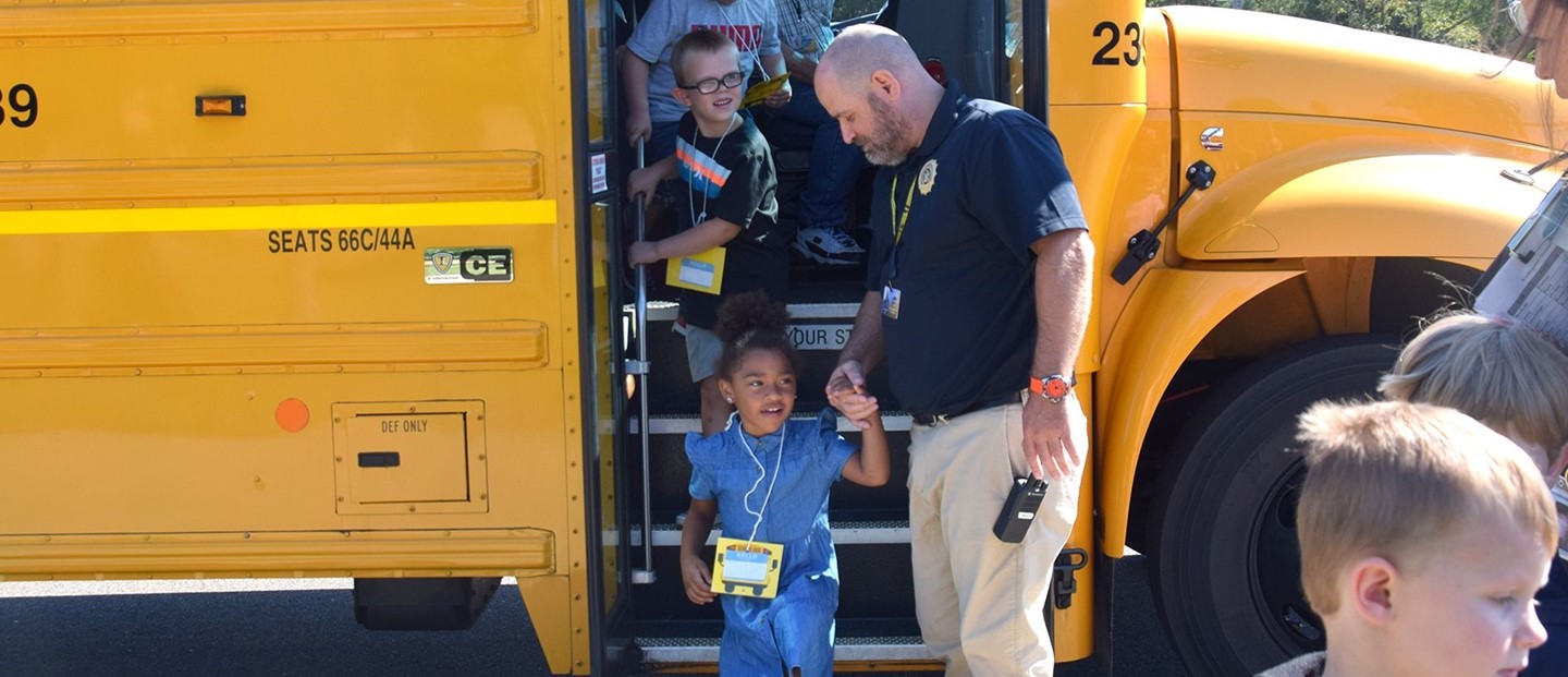 The Donnelly Elementary school resource officer helps a Kindergarten student off the bus during orientation.