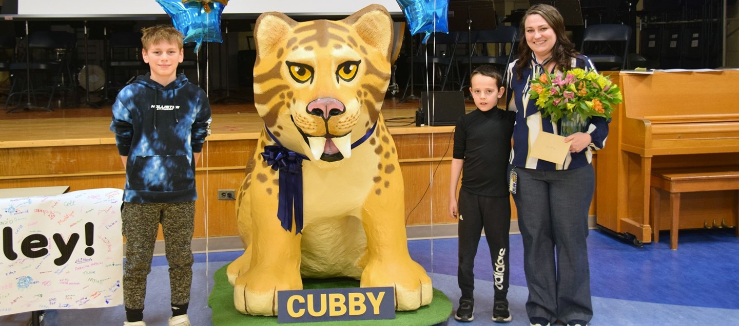Two Brookside Elementary students stand on either side of the refurbished Cubby mascot with the teacher aide who fixed him up.